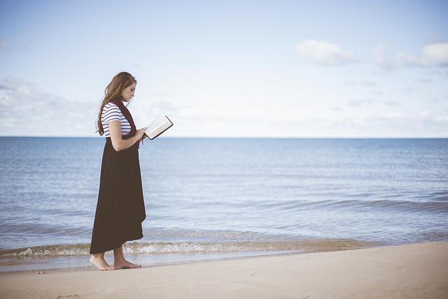 海辺で本を読む女性の画像